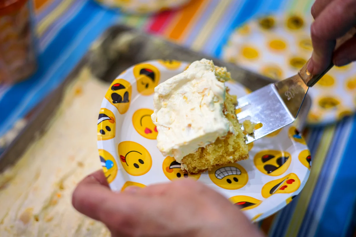 Hands serving piece of cake on emoji plate