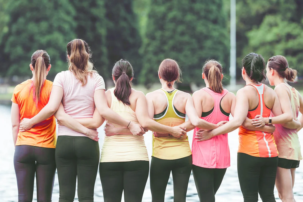 Group of women runners in pink shirts gather in solidarity and prepare to run