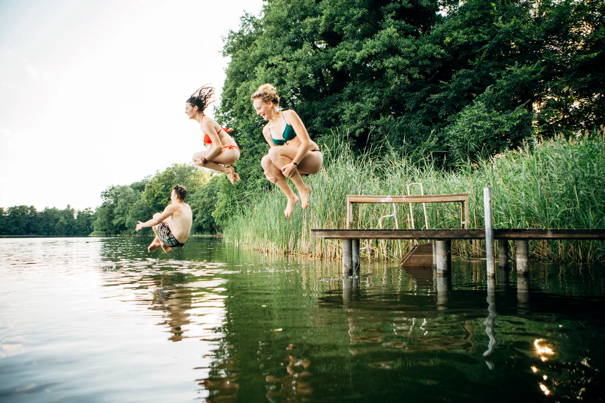 Three young adults jump from jetty into lake