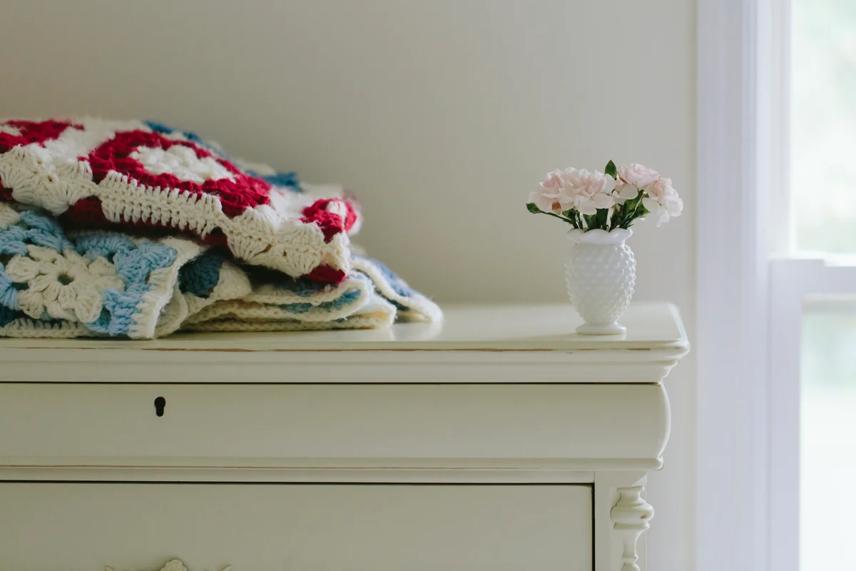 vintage afgan blankets and vase on antique dresser