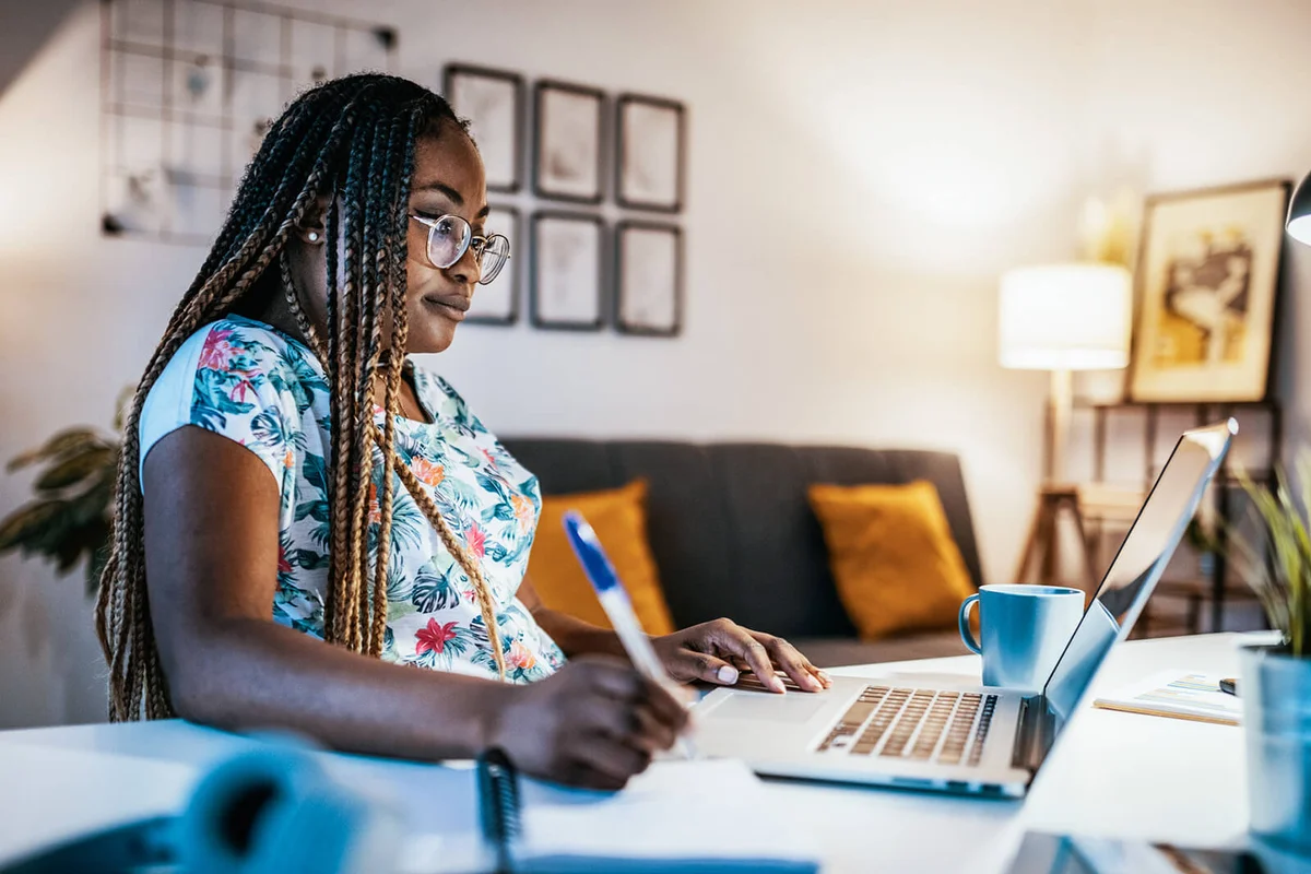 female student studying from home and taking notes from professor