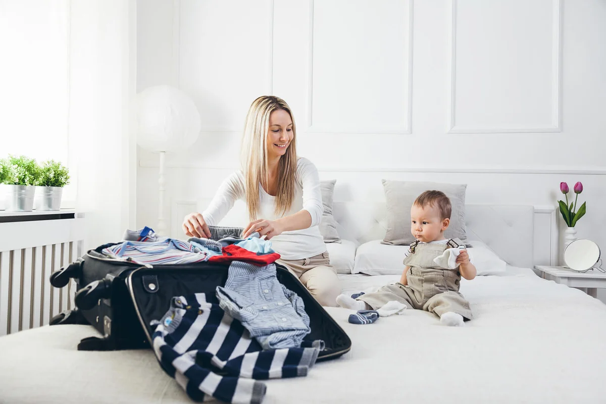 Happy mother with her child packing clothes for holiday