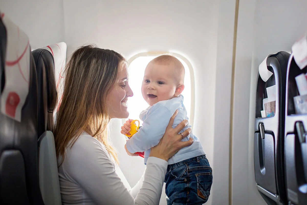 Young mom playing her baby boy on board of aircraft
