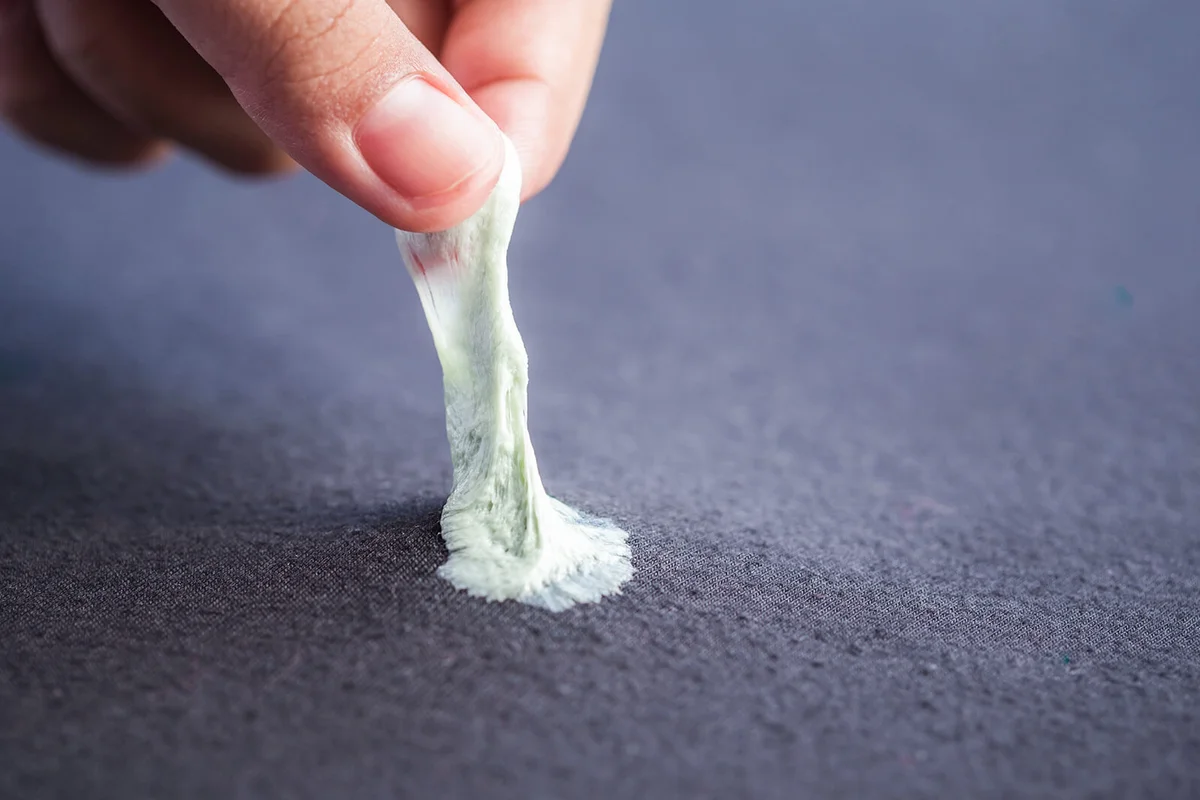 Hand removing sticky chewing gum from black textile or clothes | Photo 119061344 © Phanuwatn | Dreamstime.com