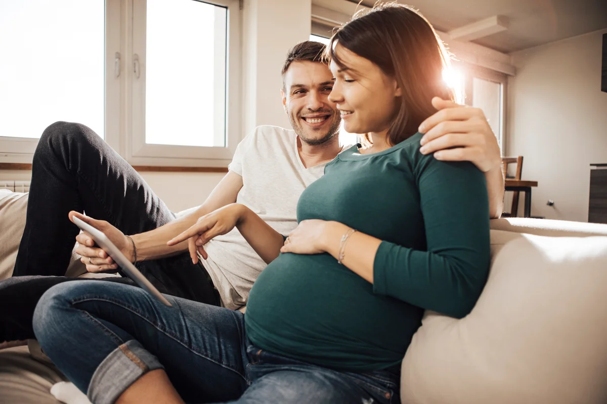 husband and wife choosing baby names on tablet computer