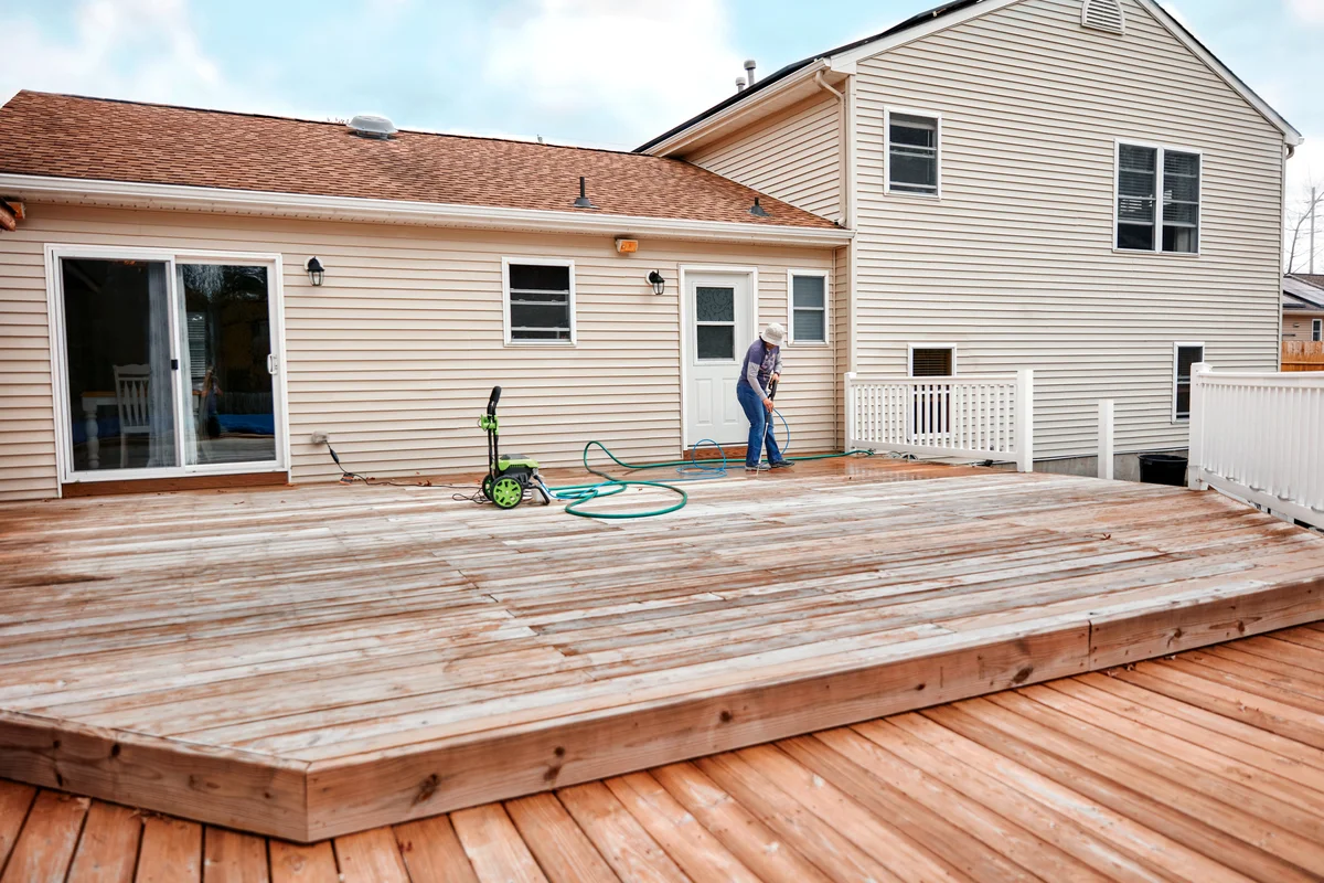 Woman Cleaning Wooden Deck With A High Water Pressure Cleaner
