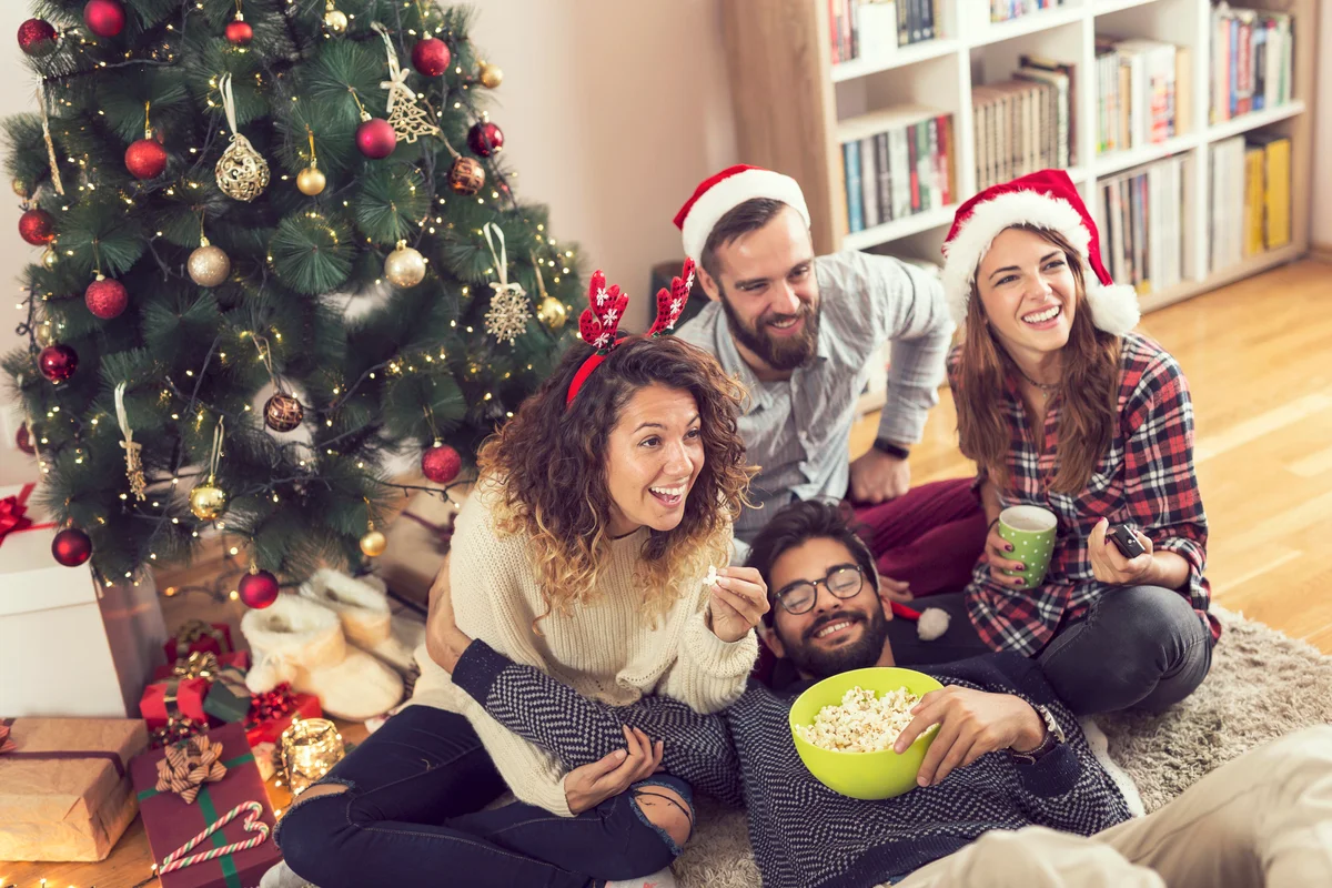 Group of friends eating popcorn and watching a Christmas movie