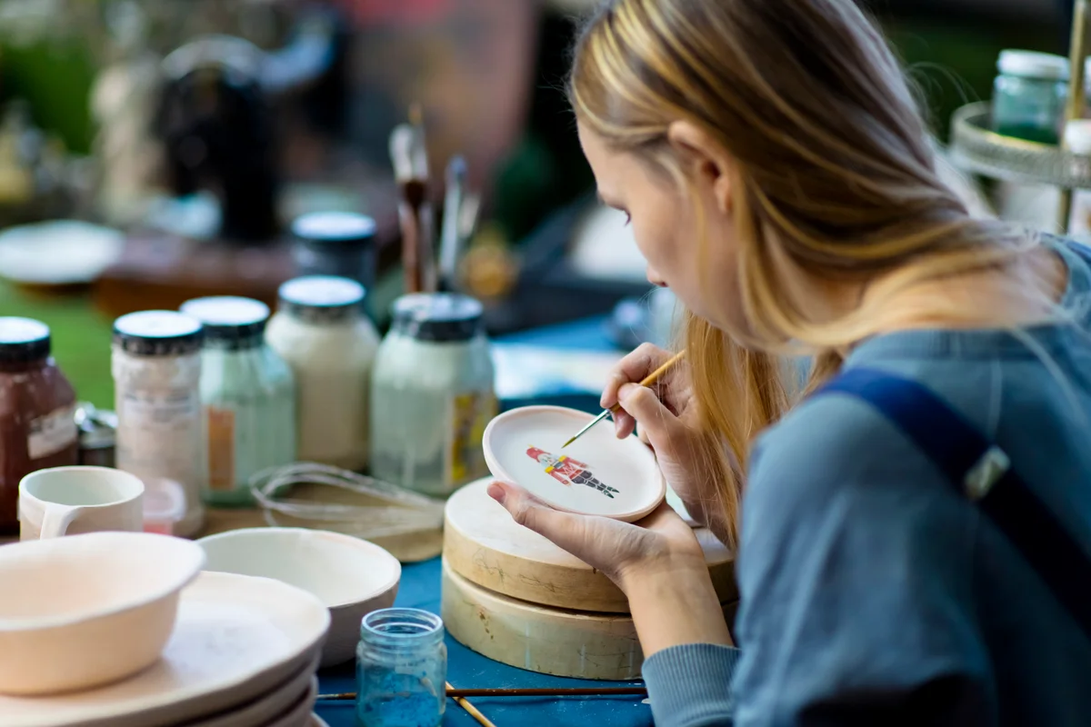 Young woman painting Nutcracker on Christmas ceramics