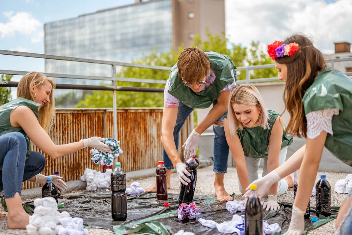 Group of young adult people making tie dye clothes outdoors on the rooftop