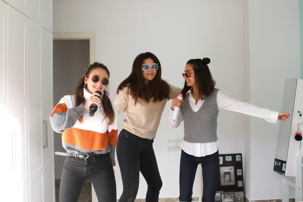 Teenage girls singing and dancing at home
