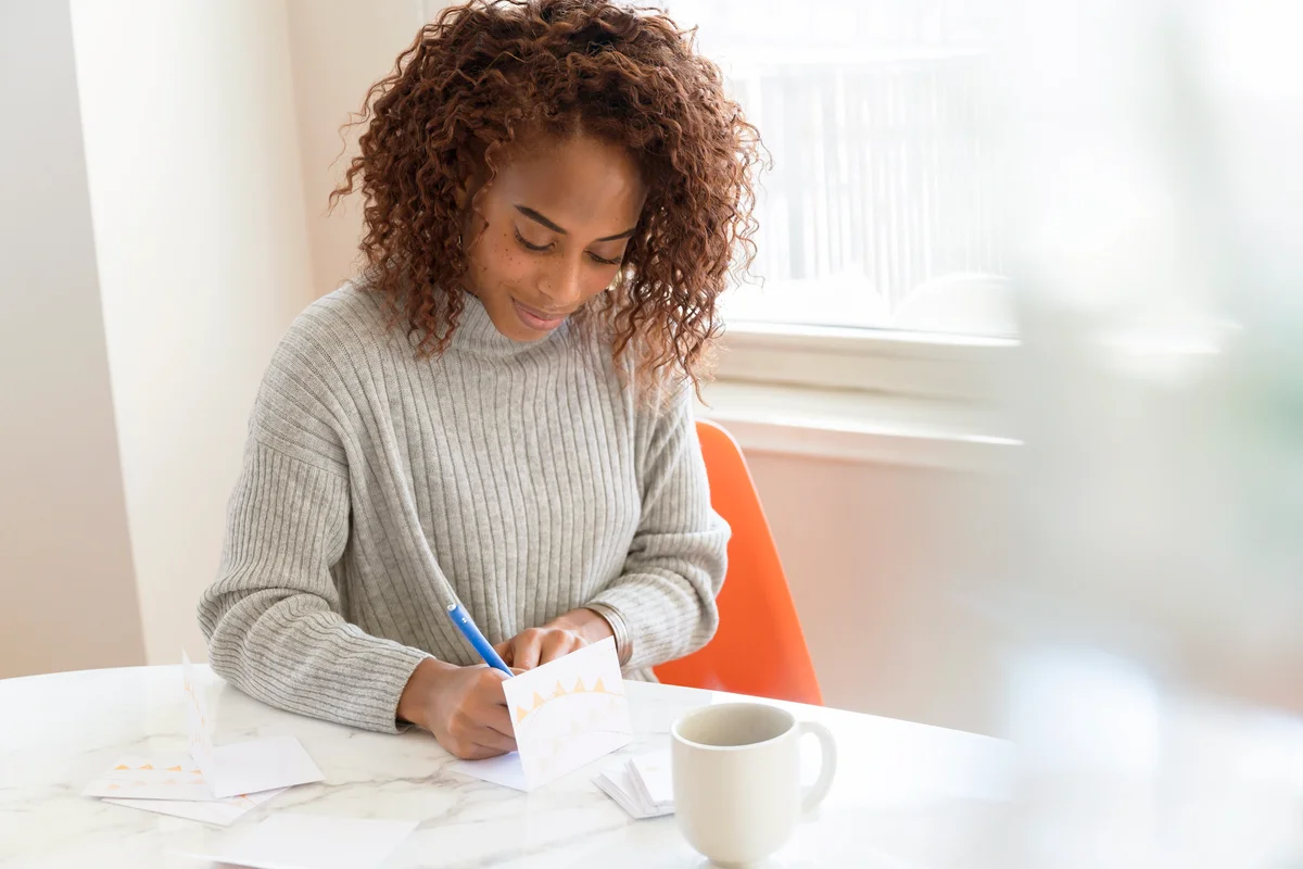 Woman writing in card on table
