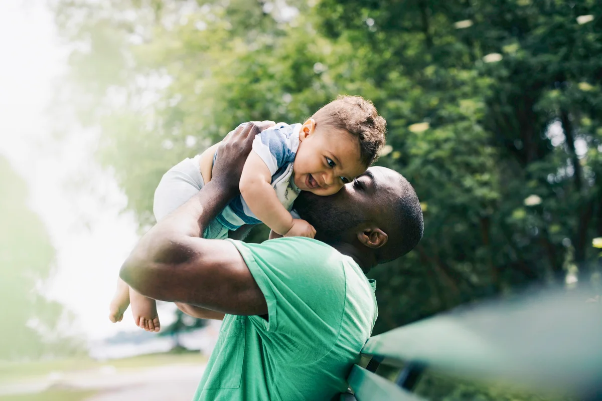 Father kissing happy son while carrying at park