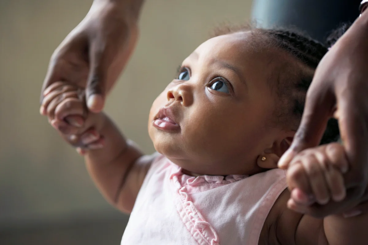 Person teaching a baby girl how to walk