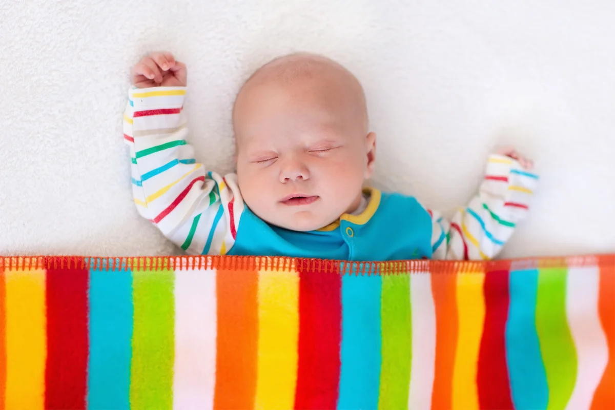 Little baby sleeping under rainbow blanket