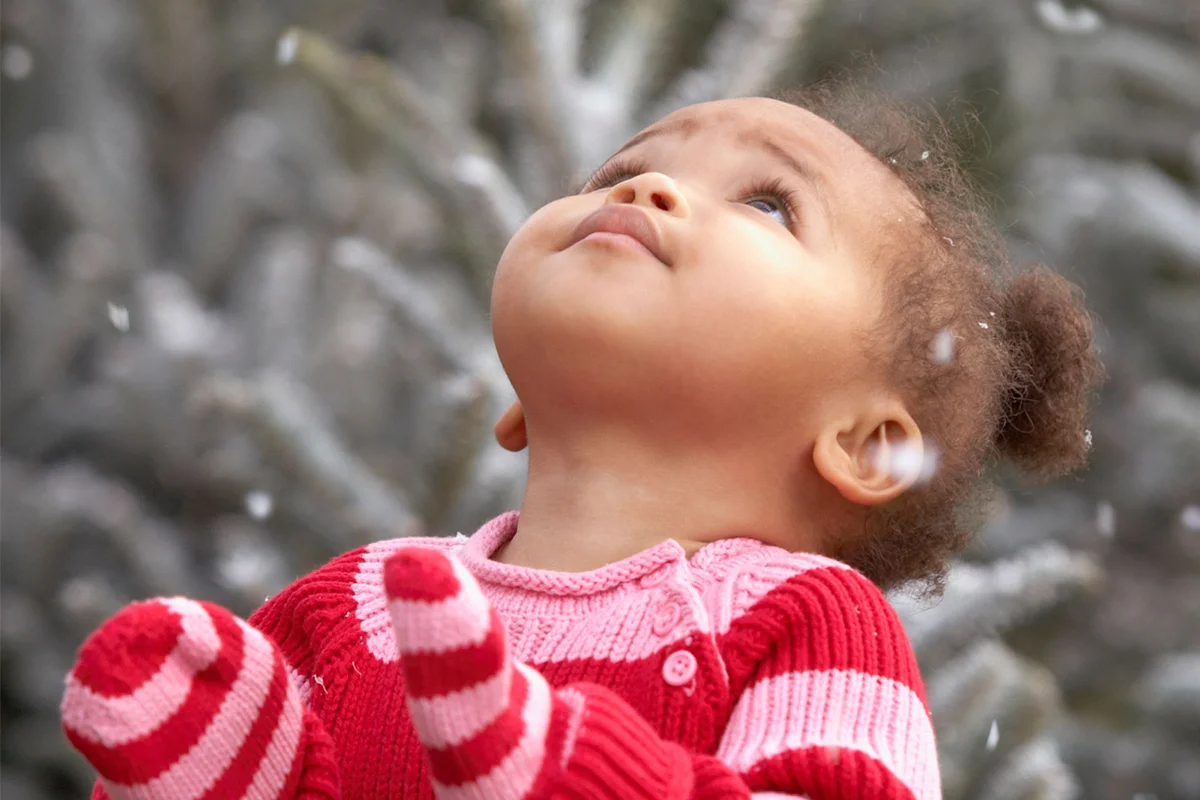baby girl looking at snow falling