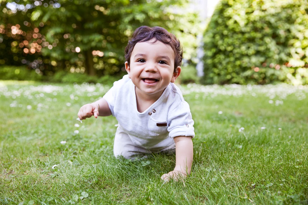 Baby boy crawling on grass, smiling