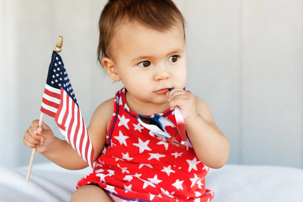 Cute Baby Girl Holding Sunglasses And American Flag