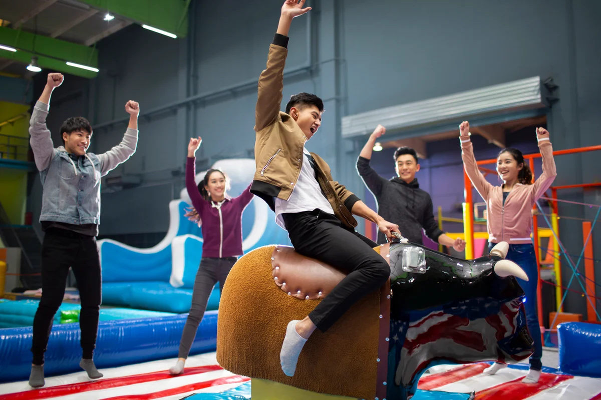 Friends riding mechanical bull at a party