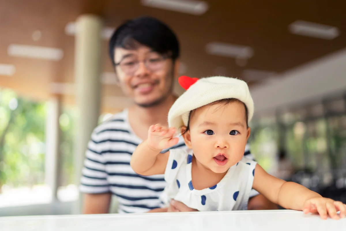 Joyful and smiling Asian baby girl playing with her father