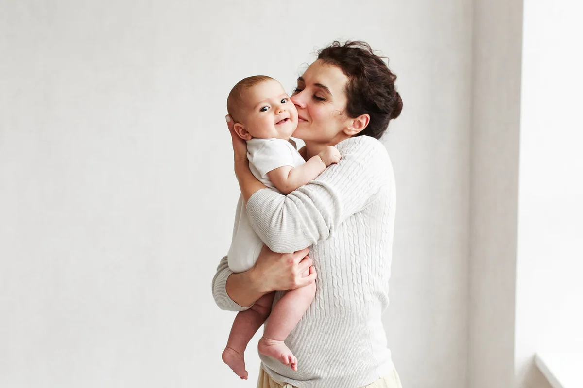 Woman holding and kissing her baby