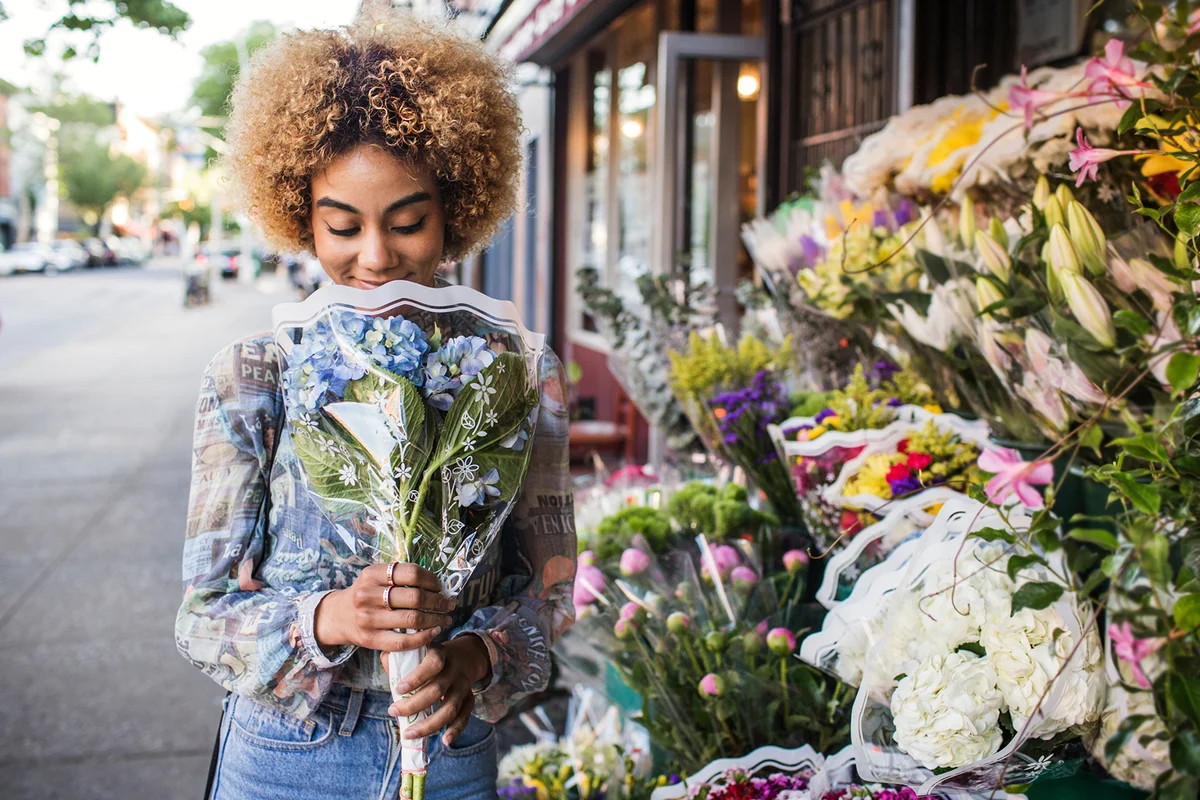 Smiling woman smelling hydrangeas outside flower shop