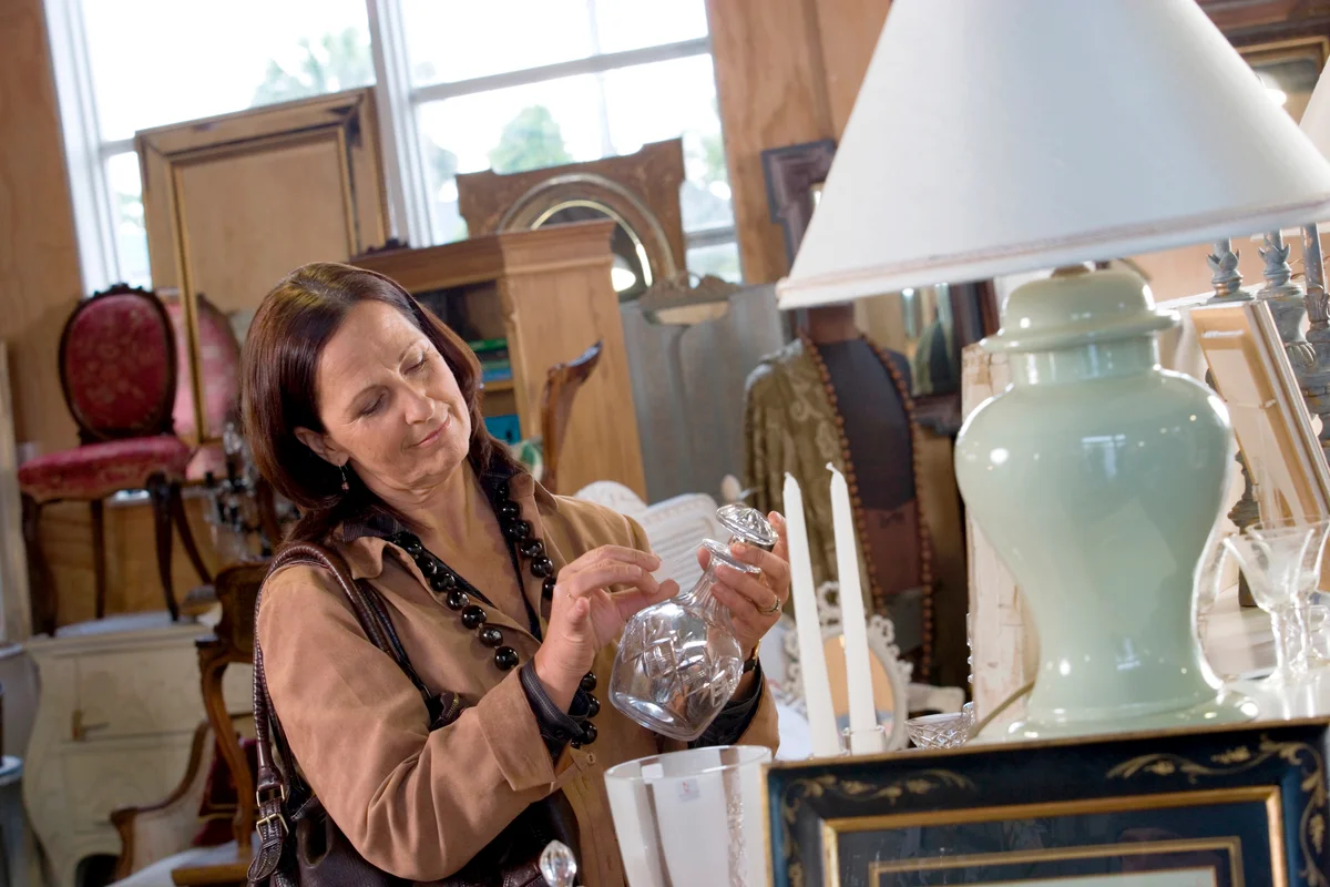 Woman holding crystal vase and checking quality by flicking with her fingers