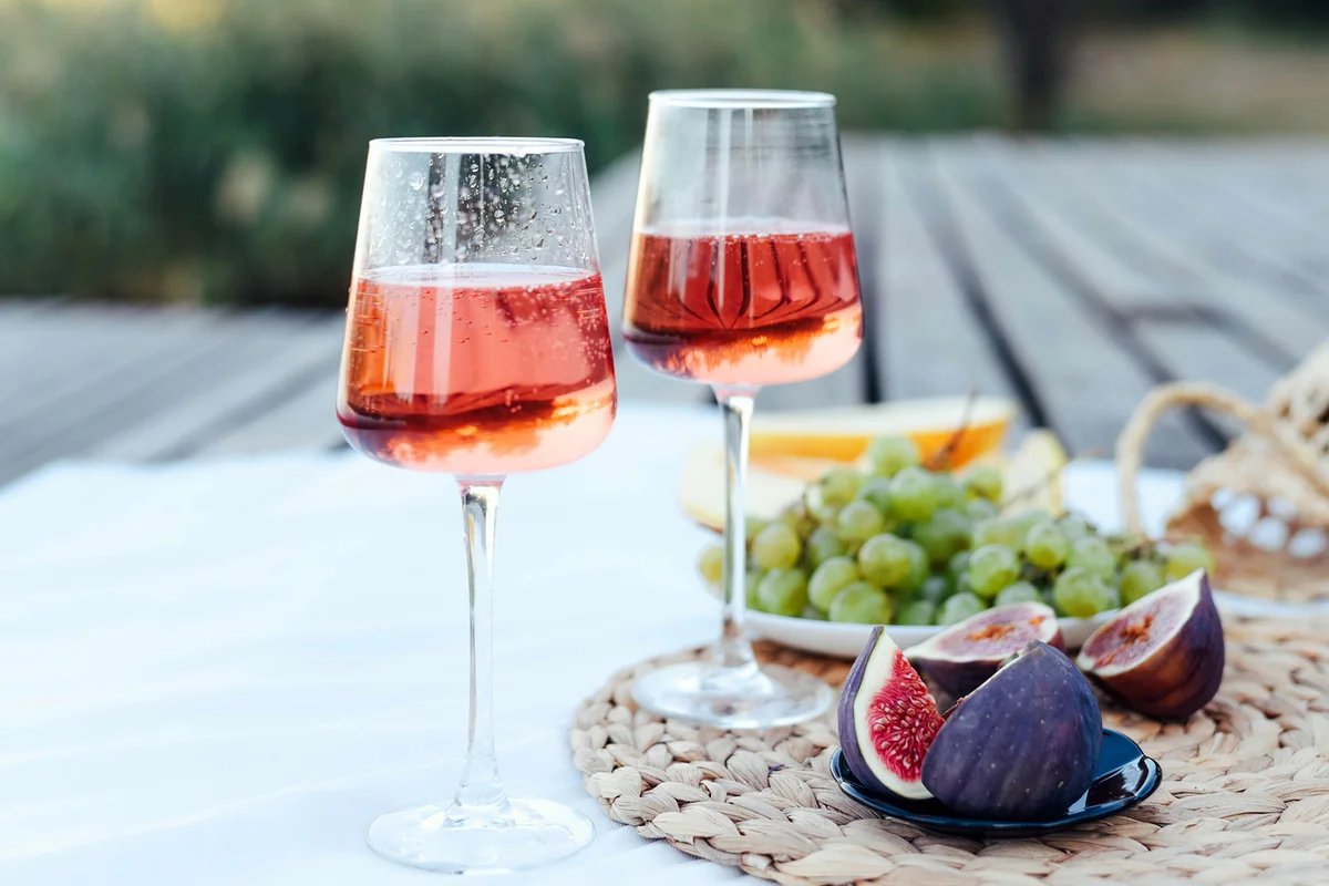 Picnic on the pier near the water with sparkling wine, figs and grapes