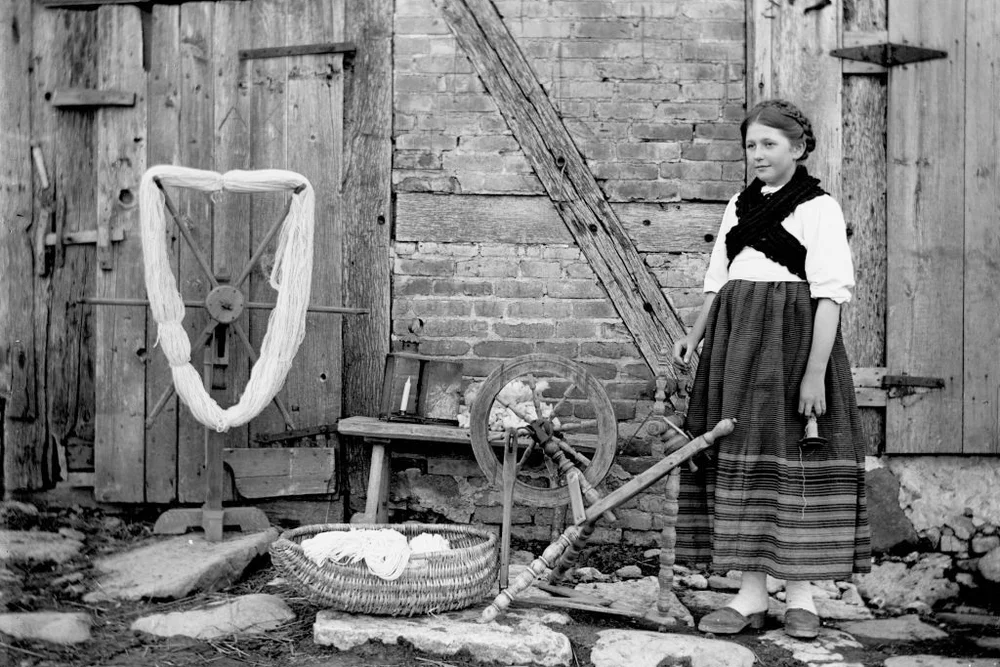 Jennie Krueger standing on stones next to a spinning wheel