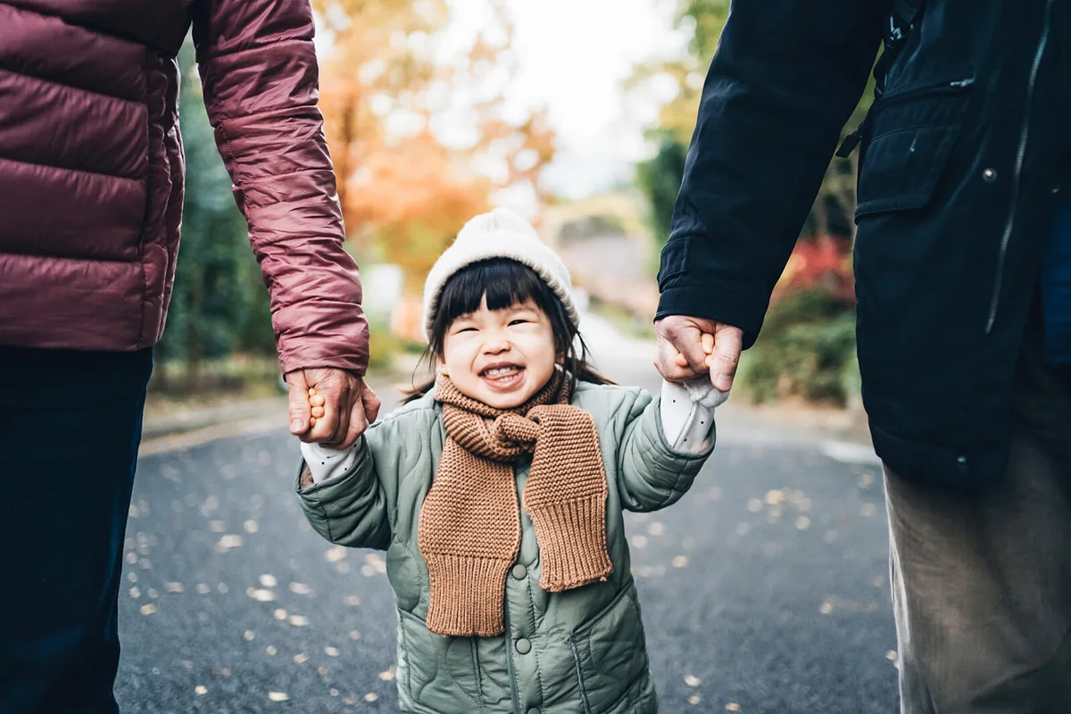 An adorable and happy little girl holding her grandparent's hand and having a relaxing walk in the park