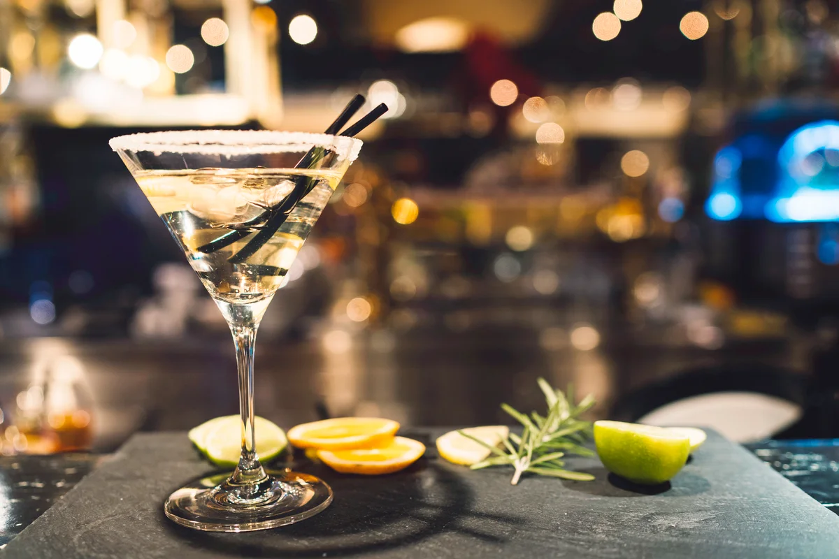 Glass of martini on a garnished surface with lemon slices and rosemary