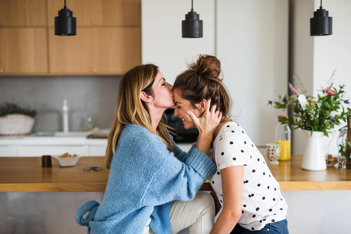 mature mother with adult daughter sitting at home