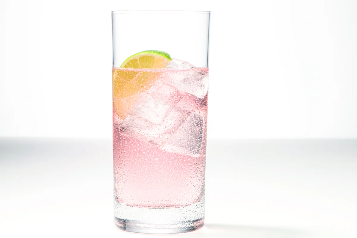 One glass of pink gin and tonic with a slice of lime