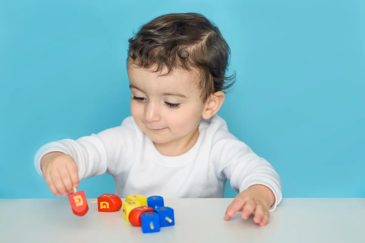 Jewish boy playing with dreidel at home