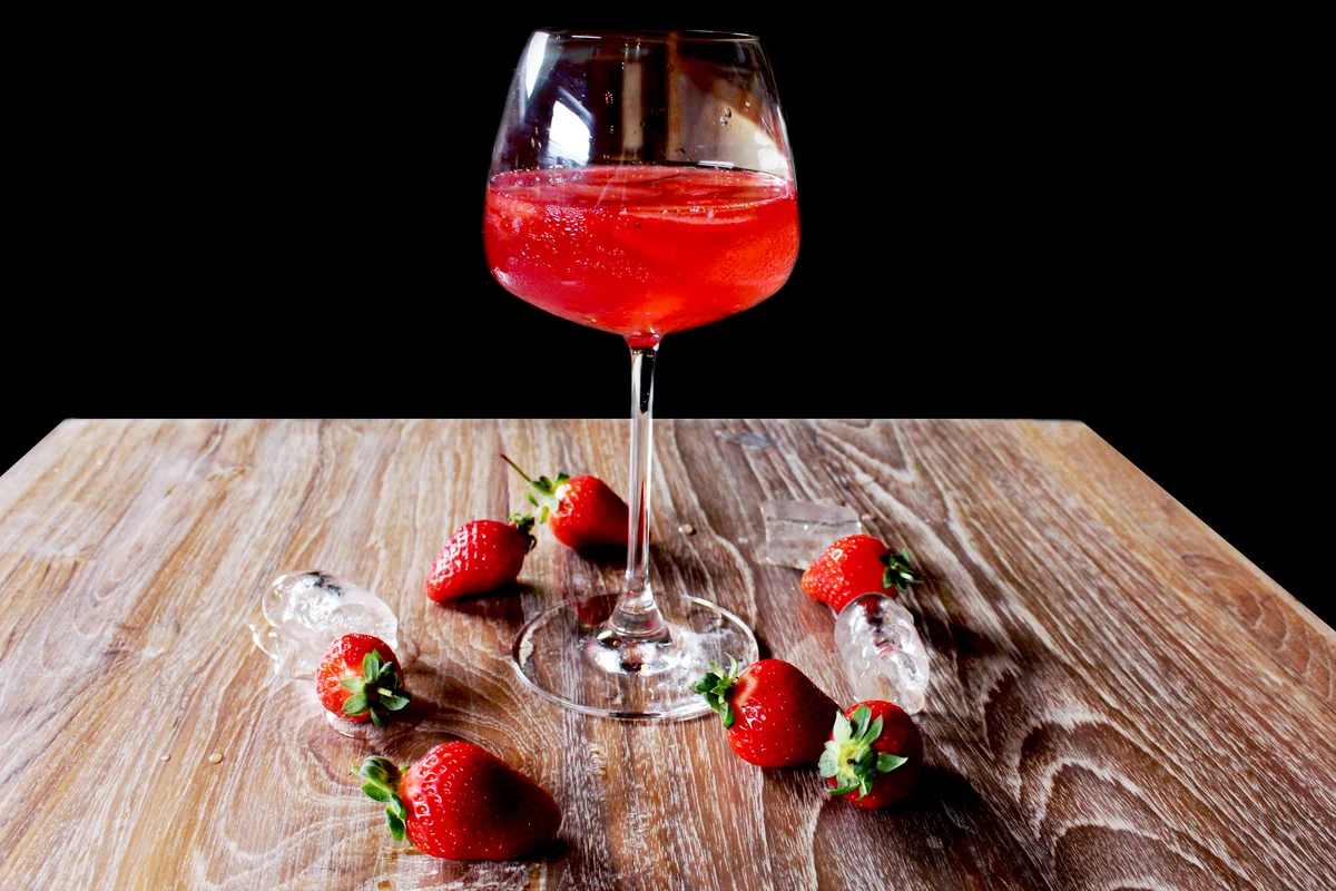 Wine with strawberries on table