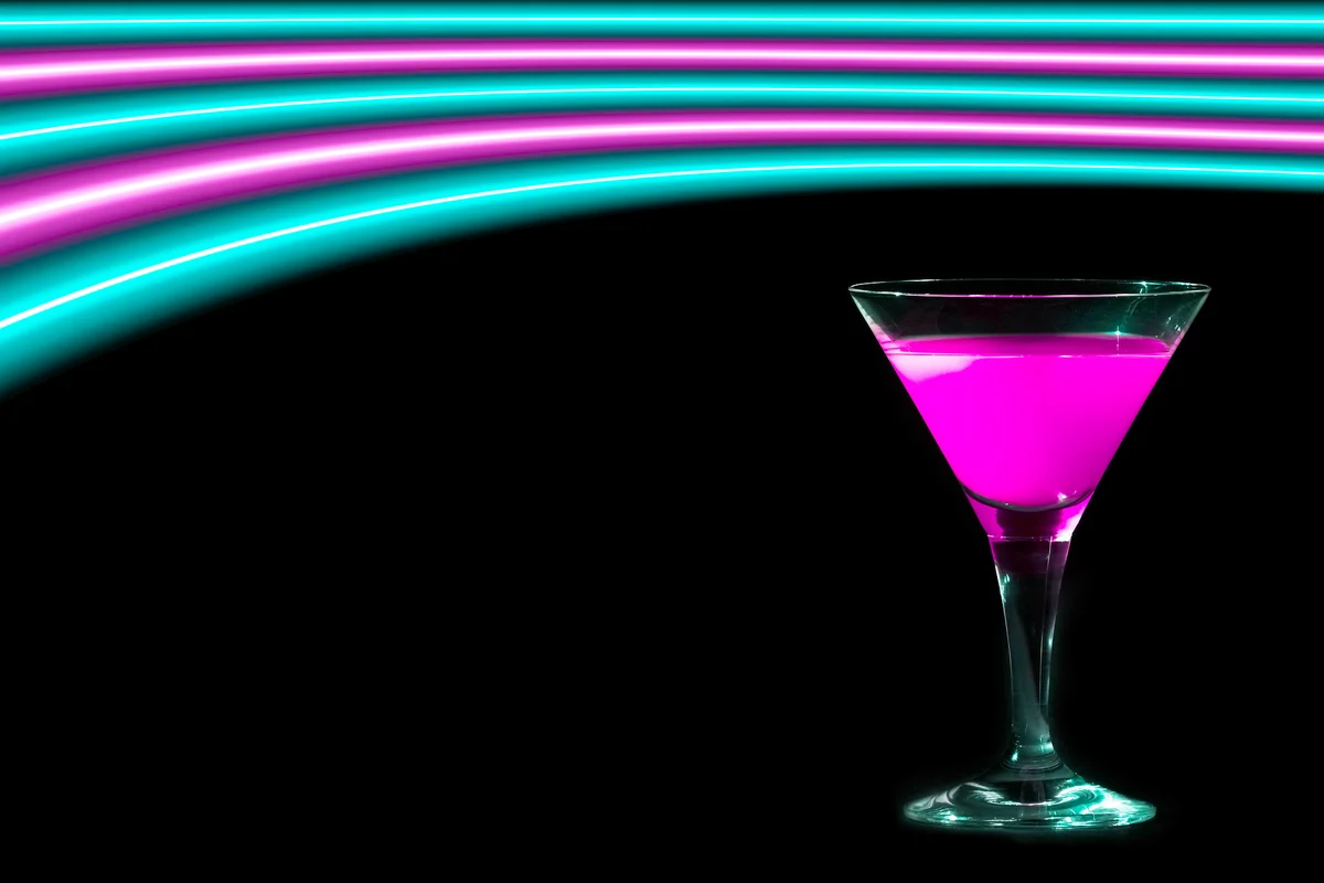Pink and turquoise neon lights over a cocktail drinking glass