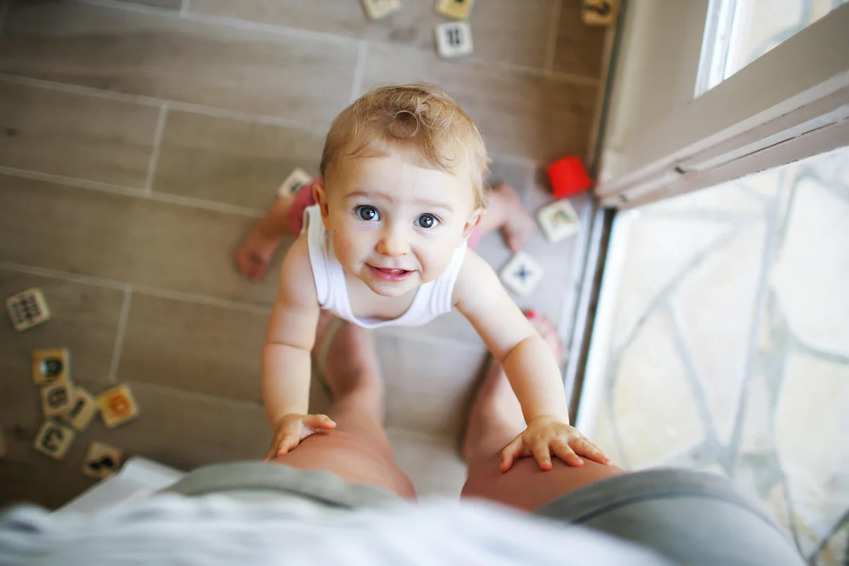 A baby girl holding her mom legs