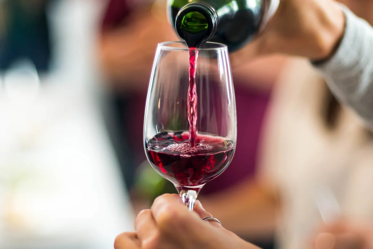 Cropped Hands Pouring Red Wine In Wineglass