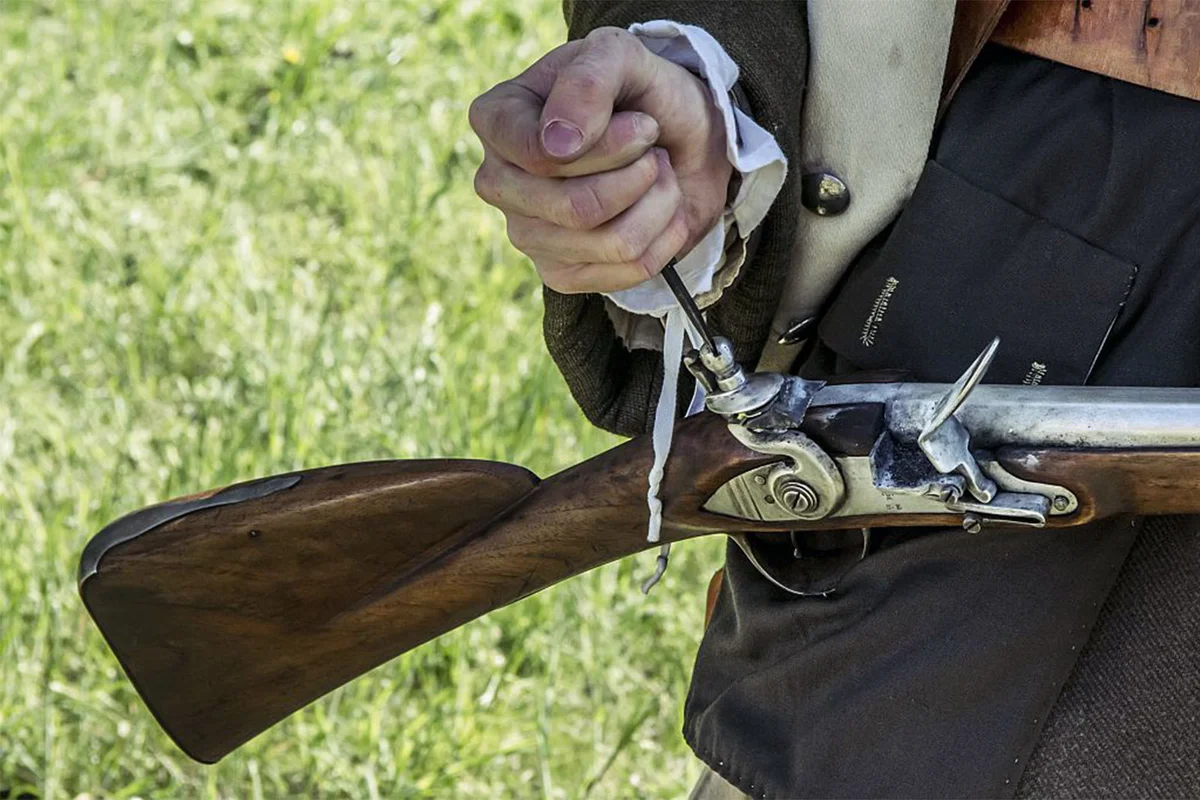 American Revolutionary War reenactment filling the flash pan of flintlock rifle