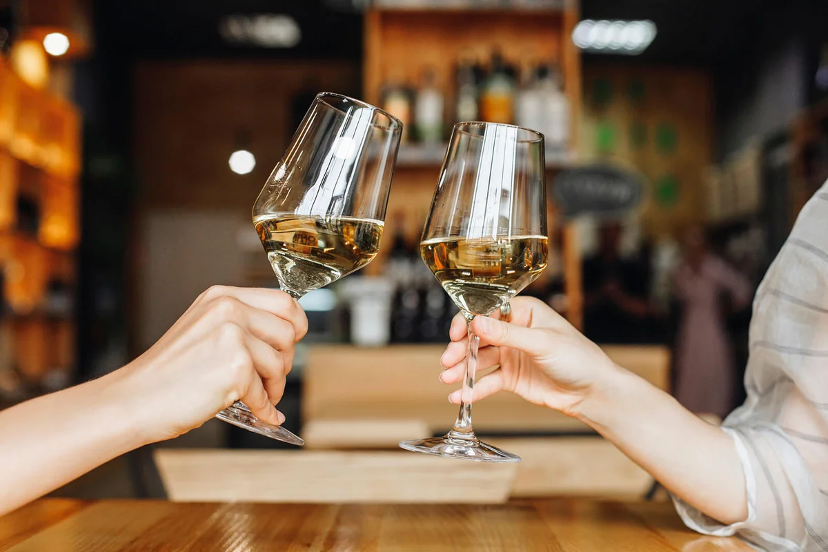 Hands of women toasting with glasses of white wine