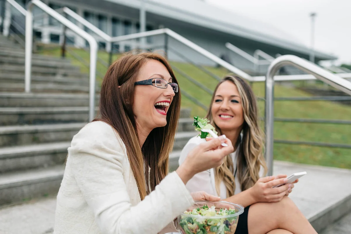 Two laughing women having lunch break outdoors