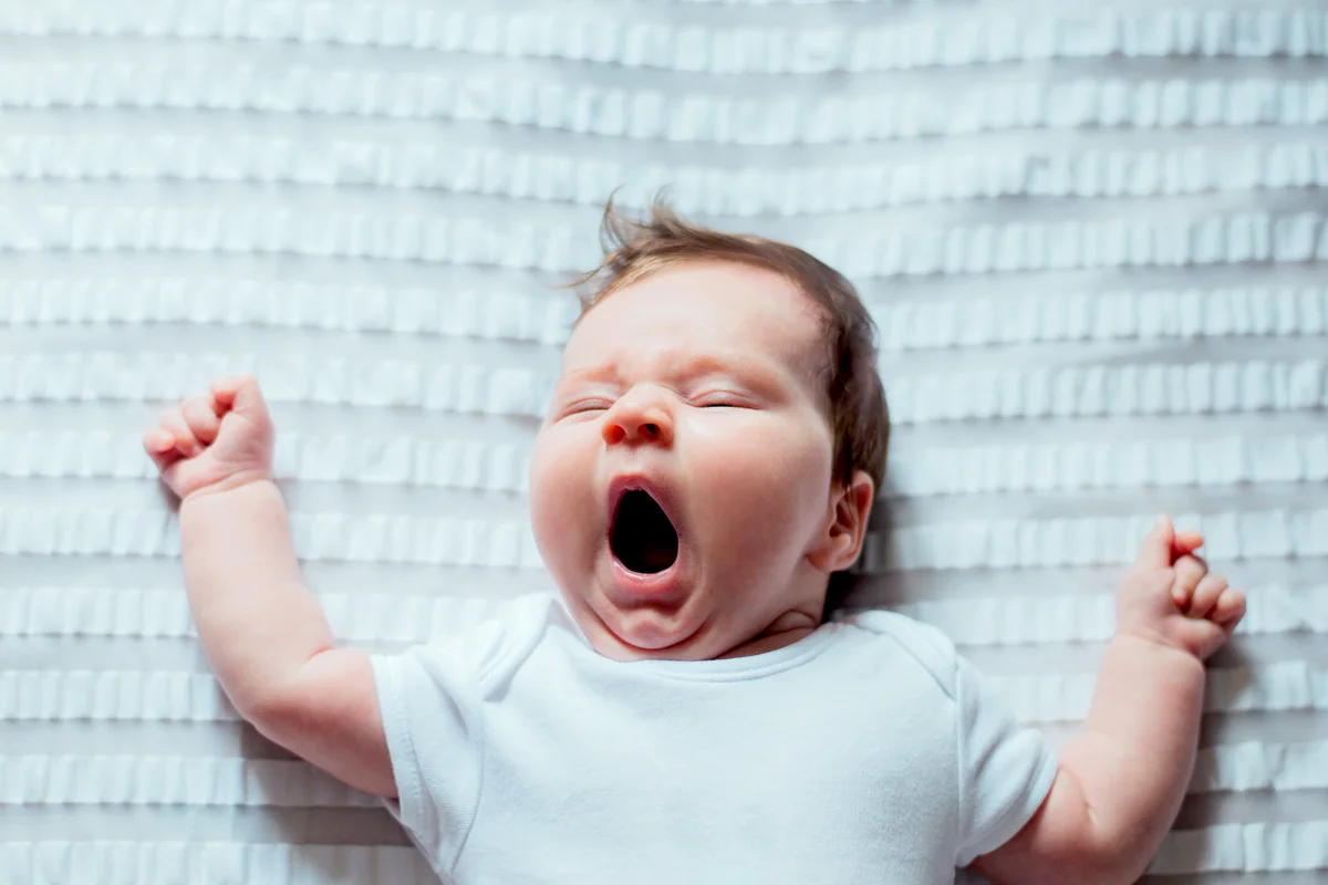 Cute Baby Yawning While Lying On Bed