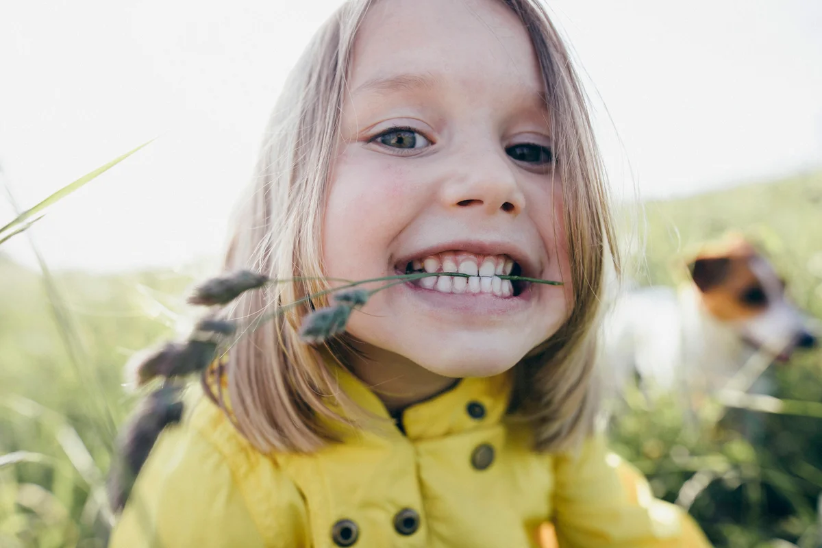 Little girl on a meadow holding blade of grass with her teeth