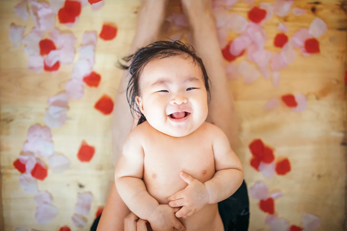 Little baby girl having a bath in a traditional wooden bathtub