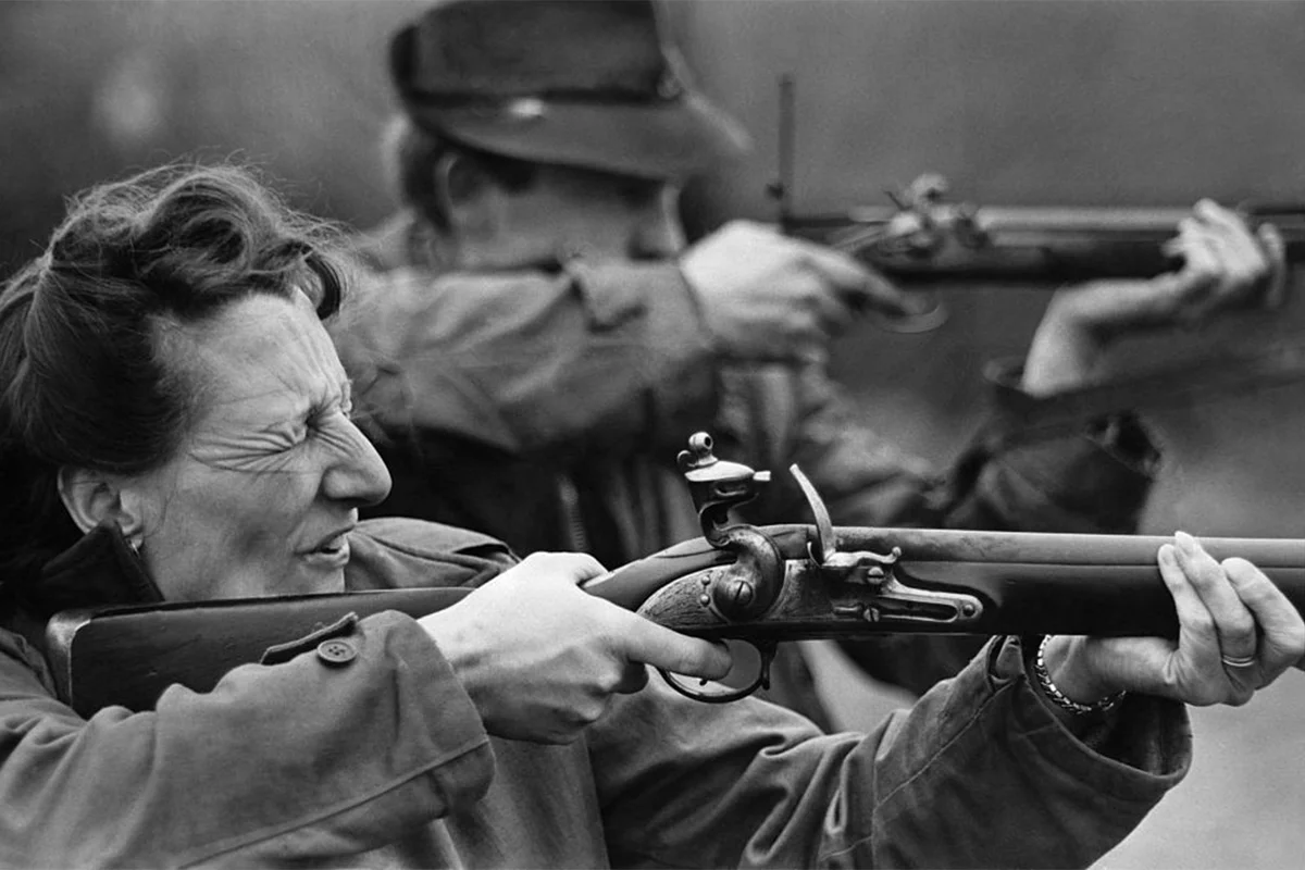 woman shooting British Army piece called Brown Bess flintlock rifle