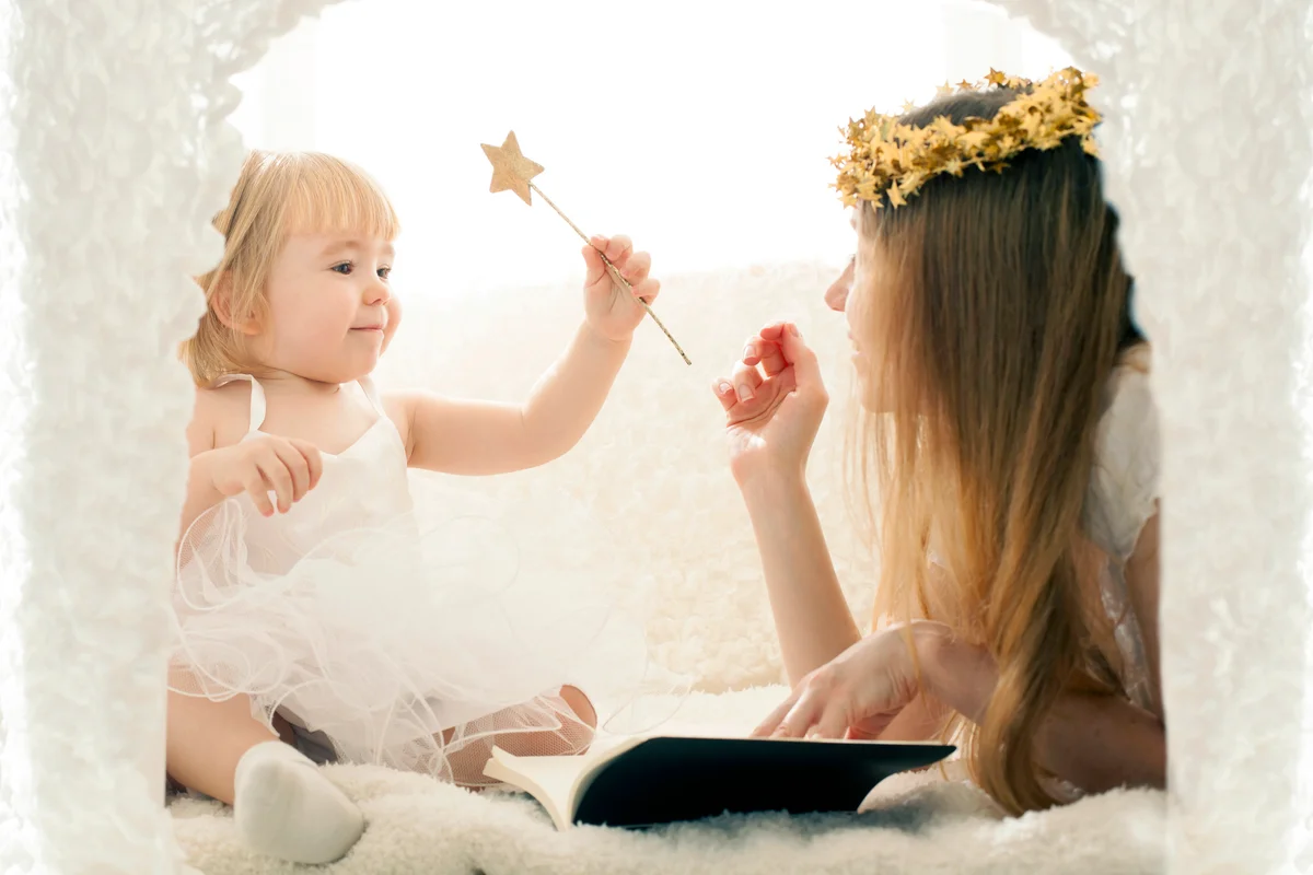 Mother and cute little girl reading in playhouse