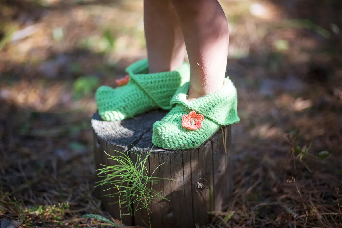 Baby feet in elf socks on a tree stump