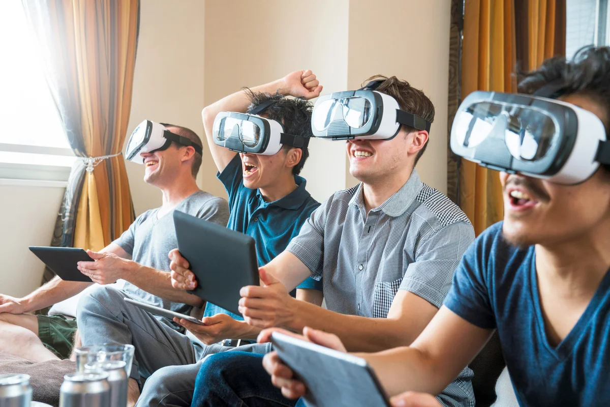 Group of friends sat on the sofa playing games using virtual reality headsets