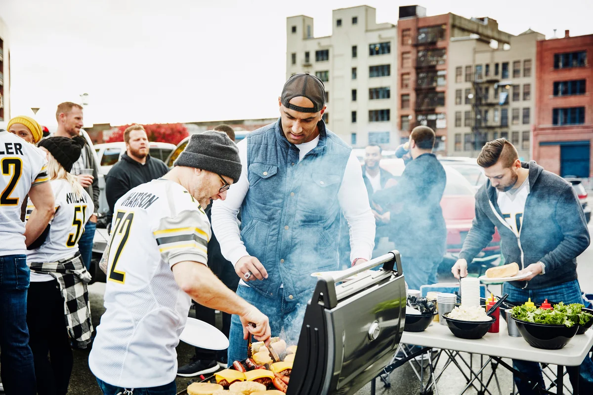 Men cooking at barbecue during tailgating party