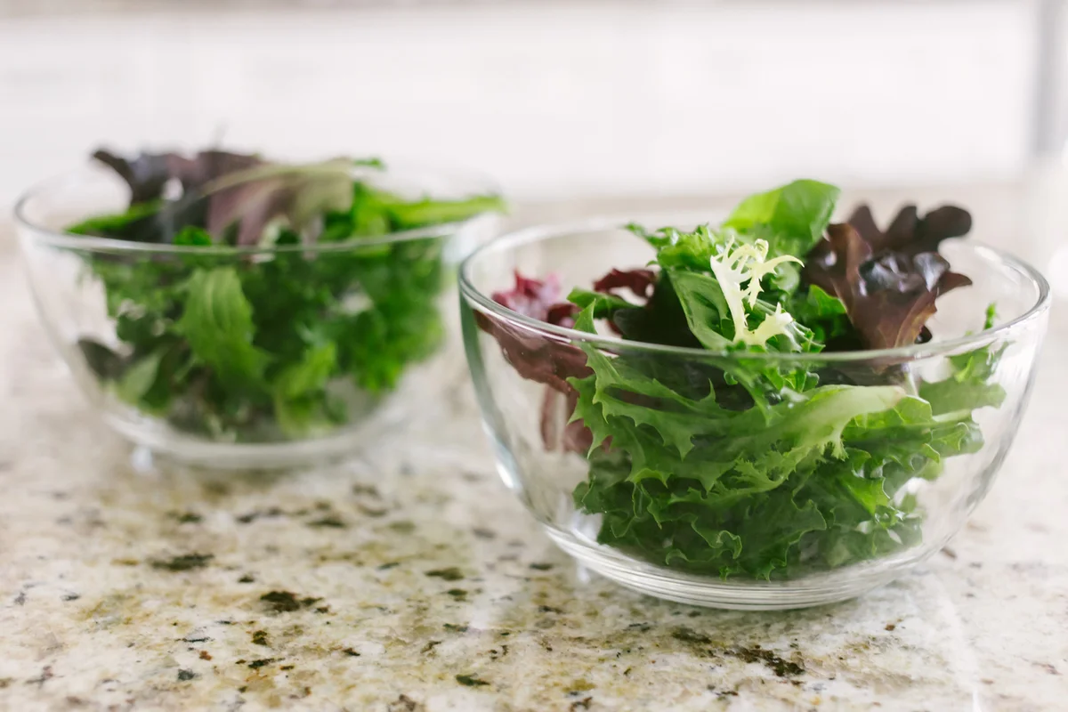 Two Glass Bowls Filled with Salad Greens on Kitchen Counter
