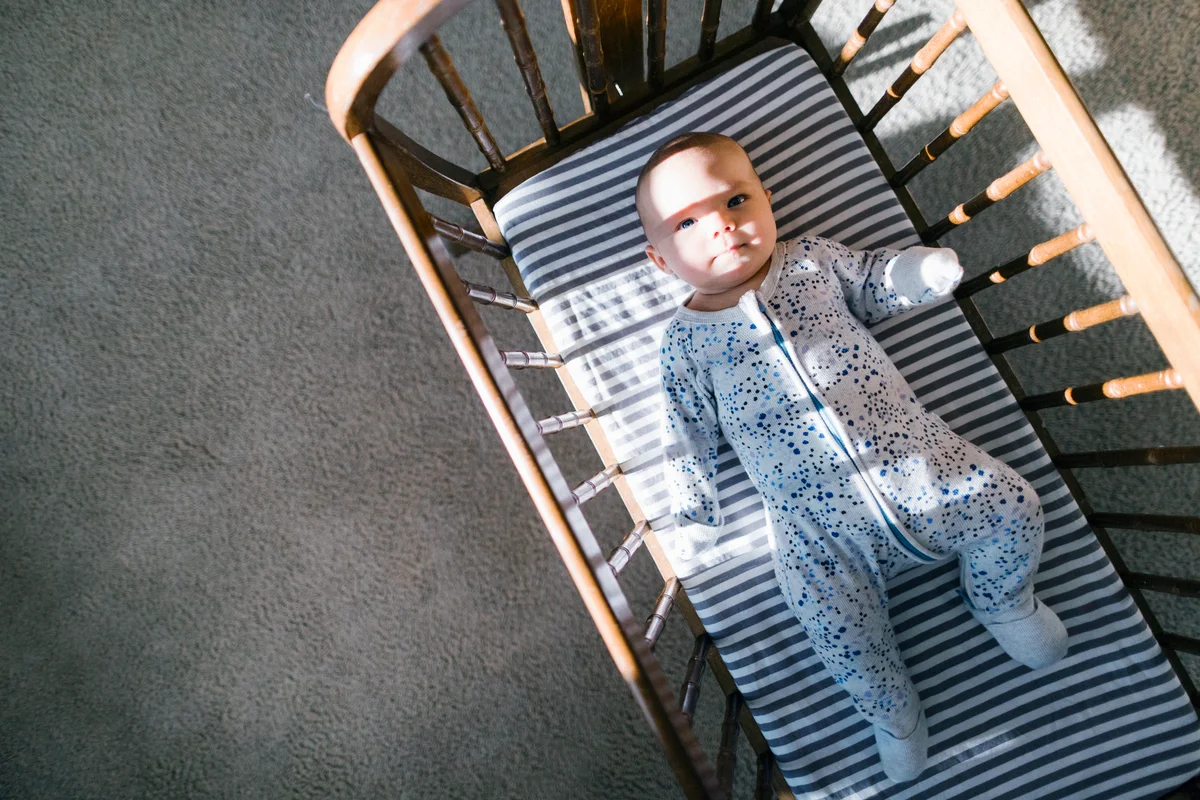 Sunlight and shadows cast on a baby laying in a wooden cradle